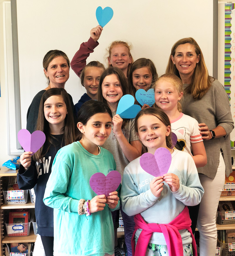 Claire Neary and Jen Morris with group of middle school girls holding hearts