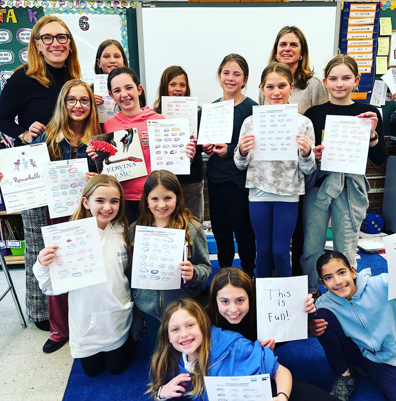 Claire Neary and Jen Morris with a group of middle school girls holding up their projects