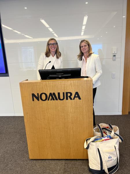 Claire Neary and Jen Morris at a podium during a corporate presentation