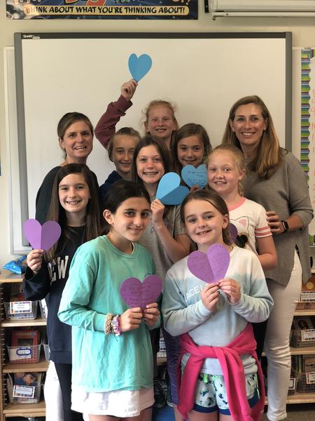 Claire Neary and Jen Morris with middle school girls holding up handwritten hearts
